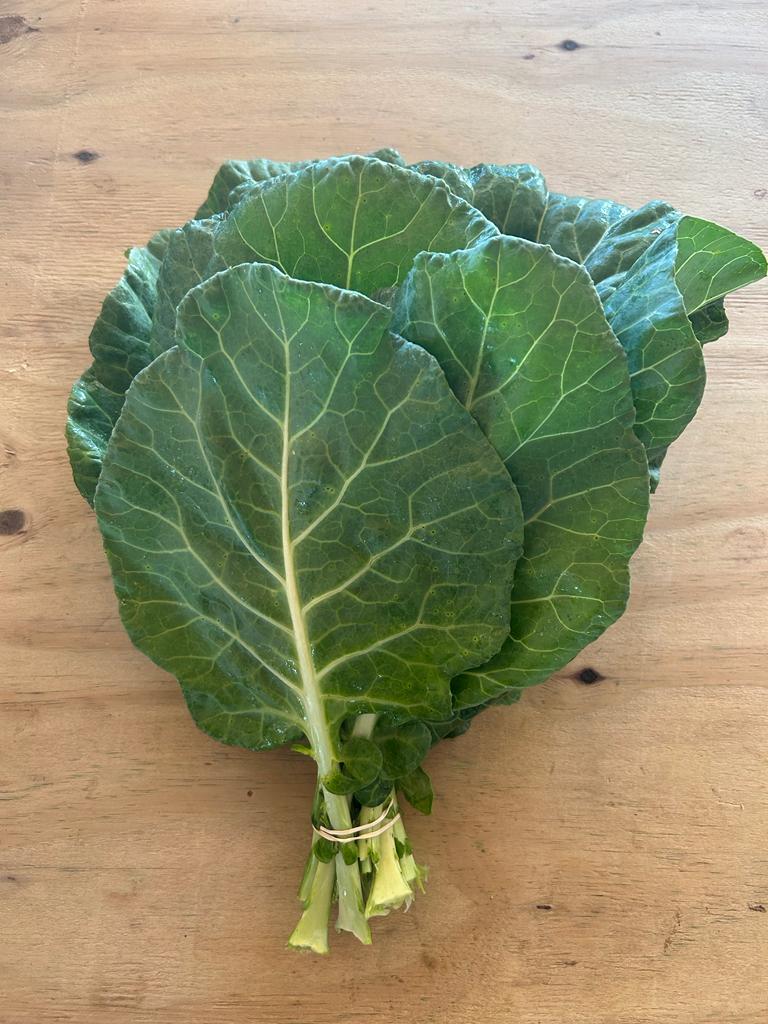 Fresh collard greens with vibrant green leaves, arranged neatly on a wooden surface, showcasing their natural texture and freshness. Ideal for healthy cooking and nutrition.